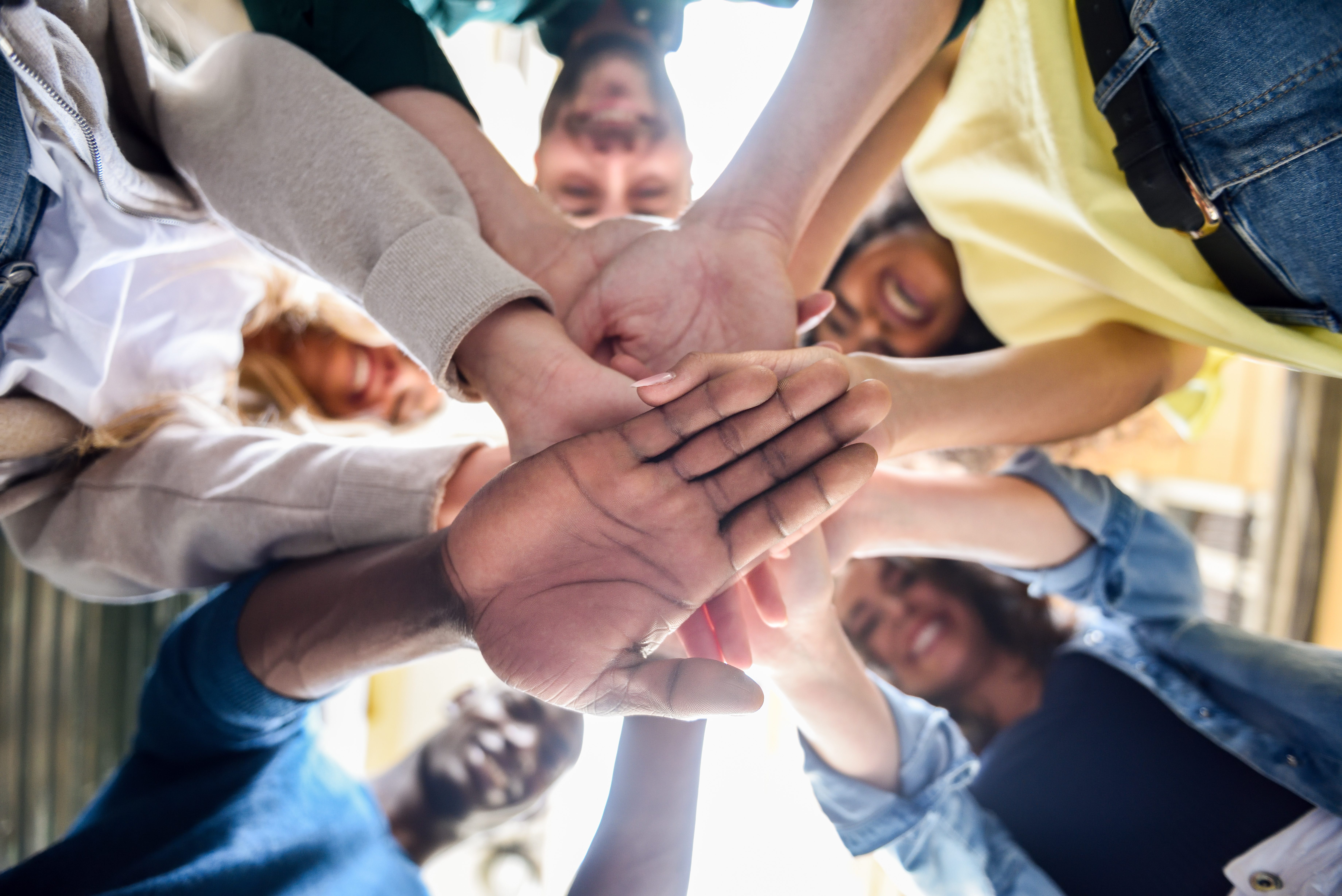 Close up view of young people putting their hands together. Friends with stack of hands showing unity and teamwork.